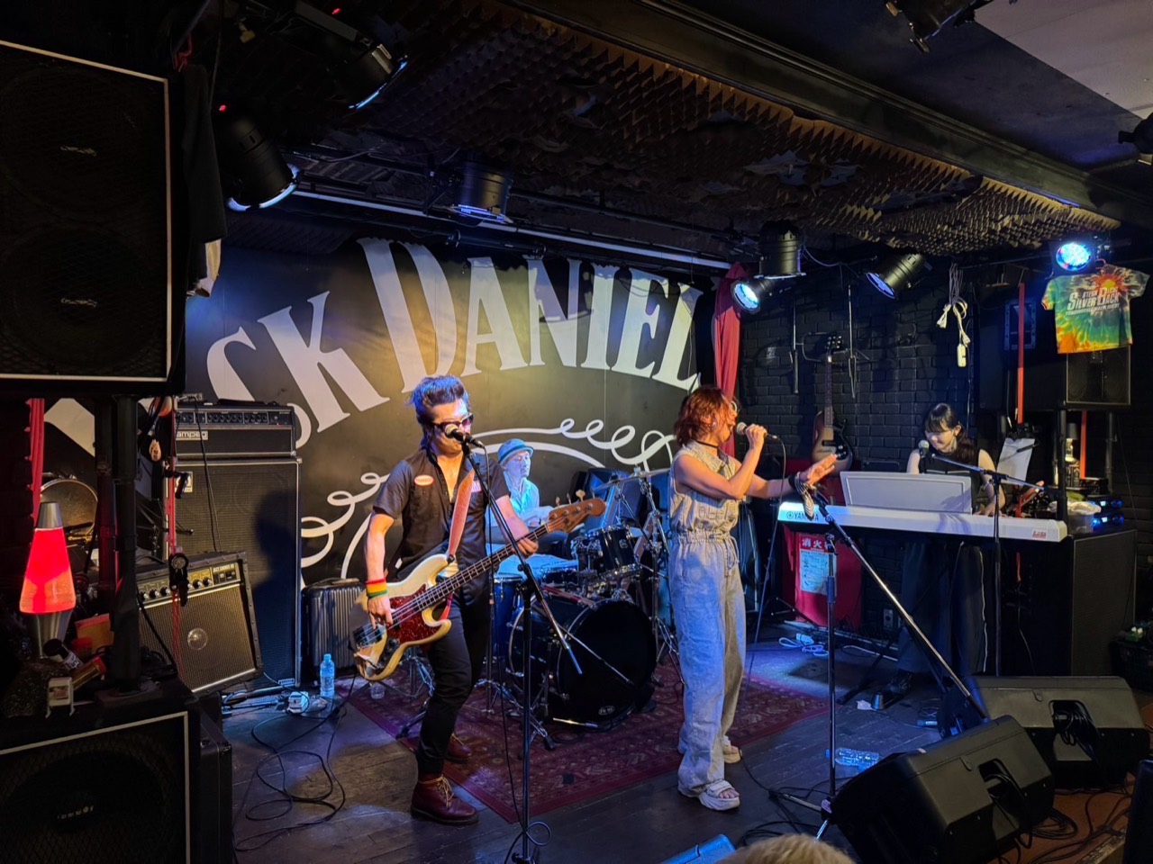 ライブハウスの照明の中で演奏するバンド全体